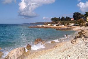 a beach with rocks and the ocean on a sunny day at Apartment Silba 17603a in Silba