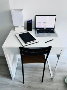 a white desk with a laptop computer and a chair at Appartement « cocooning » au bord du Loing in Nemours