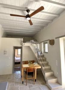 einen Deckenventilator im Wohnzimmer mit einem Tisch und einer Treppe in der Unterkunft Fournos in Kimolos