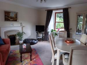 a living room with a table and a fireplace at Beautiful Farm House at the foot of Ben More. in Crianlarich