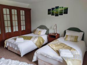 2 nebeneinander sitzende Betten in einem Schlafzimmer in der Unterkunft Beautiful Farm House at the foot of Ben More. in Crianlarich