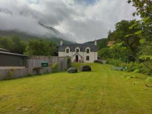 una casa con un patio de hierba delante de una casa en Beautiful Farm House at the foot of Ben More., en Crianlarich