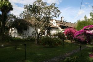 una casa blanca con flores rosas en el patio en Hotel Hacienda Baza, en Tibaná
