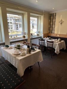 una sala da pranzo con due tavoli con tovaglie bianche di Hotel zur Altstadt a Celle