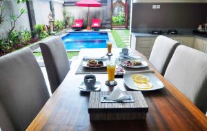 a table with food and drinks on it with a pool at Villa Kamar Madu in Seminyak
