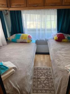 two beds in a room with a window at Синеморец Каравана Paradise in Sinemorets