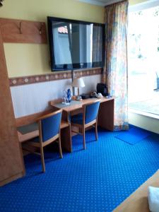 a room with a desk and chairs and a television at Hotel zur Altstadt in Celle