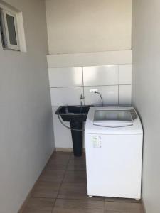 een kleine badkamer met een wastafel en een wasmachine bij Casa com 2 quartos agradáveis com ar condicionado in Foz do Iguaçu