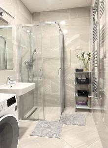 y baño con ducha, lavabo y lavadora. en VIT Apartment - Free Parking - O2 Arena, en Praga