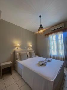 a bedroom with a large white bed with a window at Fenareti Apartments in Skala Eresou