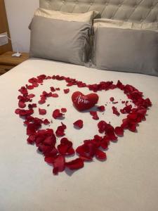 a heart made out of red roses on a bed at Estúdio no Condomínio Acquaville in Ilhabela