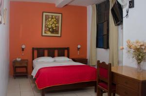 um quarto com uma cama com uma parede laranja em Hotel San José em Piura