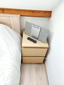 ein Nachttisch mit einem Computer neben einem Bett in der Unterkunft Studio Autonome Mont Saint Guibert in Mont-Saint-Guibert