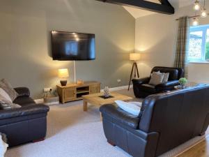 a living room with two couches and a flat screen tv at Cragside Cottage in Troutbeck