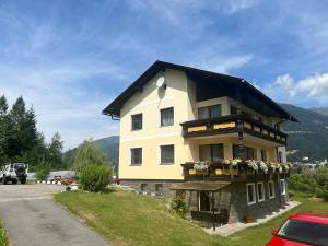 a building with a black roof and flowers on it at Schöne Ferienwohnung, Familienfreundlich 130m2 in Greifenburg