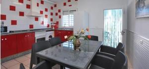 una cucina con tavolo in vetro, sedie e armadi rossi di Casa Enrique a Cadice