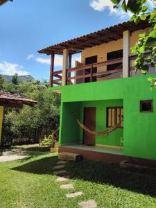 una casa verde y blanca con patio en Pousada Abacateiro, en Vale do Capao