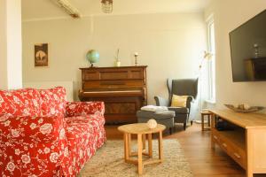 ein Wohnzimmer mit einem roten Sofa und einem Klavier in der Unterkunft Pension Gestüt Lindenhof in Templin