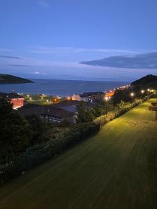 uma vista para uma cidade à noite com o oceano em Sunnyside View Apartment -modern & cosy apartment with magnificent views to match em Youghal