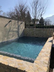a swimming pool with a stone wall and blue water at La Grange à Roger in Myans