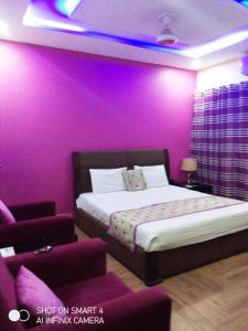 a bedroom with purple walls and a bed and a couch at Hotel Versa Appartments lodges Gulberg3 in Lahore