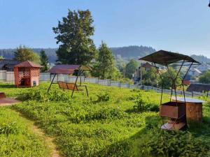 einen Garten mit zwei Bänken und einem Sonnenschirm in der Unterkunft Апартаменти "Ілона" в центрі Східниці in Schidnyzja