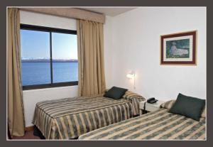 a hotel room with two beds and a large window at Hotel Bariloche Flat in San Carlos de Bariloche