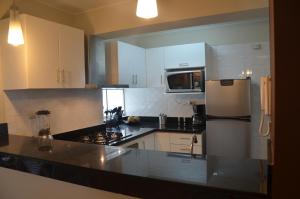 a kitchen with white cabinets and a refrigerator at Miraflores Apartments in Lima