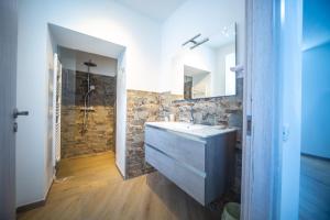 bagno con lavandino e parete in pietra di Around Lago Maggiore rooms a Reno Di Leggiuno
