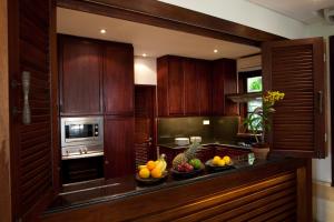 a kitchen with wooden cabinets and fruits on a counter at Villa Amani in Tanah Lot
