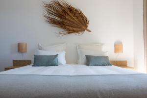 um quarto com uma cama grande com lençóis brancos e almofadas azuis em Al' Casas do Sal em Alcácer do Sal