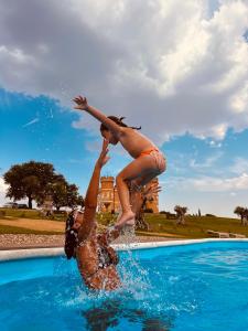 dos personas están saltando a una piscina en Castillo de Monte la Reina Posada Real & Bodega, en Toro