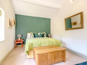 a bedroom with a bed with a green wall at The Paddock in Shipston-on-Stour