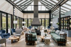 uma sala de estar com jardim de Inverno, mobiliário e janelas em Grand Hotel Opduin em De Koog