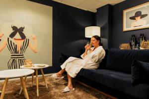 a woman sitting on a couch in a room with a mannequin at Grand Hotel Opduin in De Koog