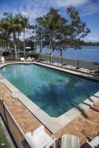 a swimming pool with chairs and the water at Colonial Tweed Holiday & Home Park in Tweed Heads