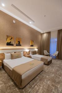 Cette chambre comprend deux lits et un bureau. dans l'établissement Merida Hotel Baku, à Baku