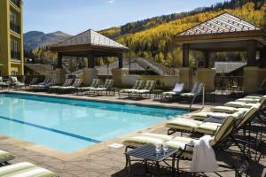 une grande piscine avec des chaises longues et des parasols dans l'établissement Platinum Vail Ritz-carlton 3 Bedroom Mountain Residence Just One Block From The Eagle Bahn Gondola, à Vail