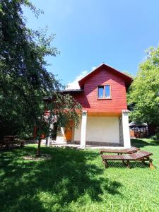 a red house with a picnic bench in front of it at Садиба над потічком in Oriv