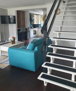 a blue couch in a living room next to a staircase at Four Seasons by the Sea in Peacehaven