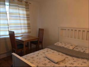 a bedroom with a bed and a table and a window at Nikolay’s House in Bristol