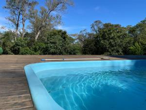 a swimming pool with a wooden deck and the water at Sítio Hortênsias in Três Coroas