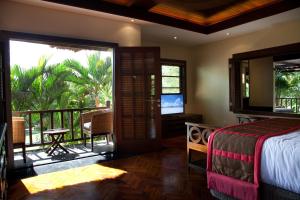 1 dormitorio con 1 cama y balcón con TV en Villa Amani, en Tanah Lot