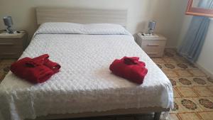 dos toallas rojas están sentadas en una cama blanca en Casa Staropoli, en Sciconi