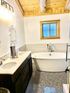 y baño con bañera, aseo, lavamanos y bañera. en Spacious luxurious log cabin near Cooperstown NY, en Oneonta