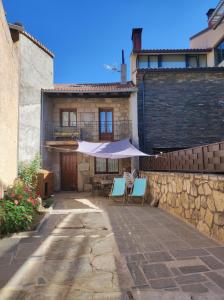 a patio with two chairs and an umbrella in front of a building at CASA RURAL EL TOLEO in Hoyos del Espino