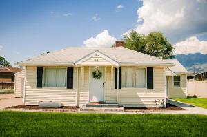 una casa blanca con puerta y césped en Cozy Cottage Retreat in the Heart of Utah Valley, en Orem