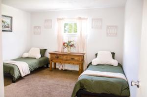 Cette chambre comprend deux lits et une table avec une fenêtre. dans l'établissement Cozy Cottage Retreat in the Heart of Utah Valley, à Orem