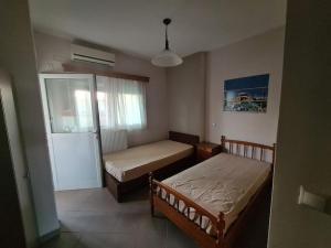 - une chambre avec 2 lits et une porte coulissante en verre dans l'établissement Village Giorgos, à Áyios Spirídhon
