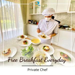 a chef preparing food in a kitchen with plates of food at Luxury Dana Beach Resort & Spa in Danang